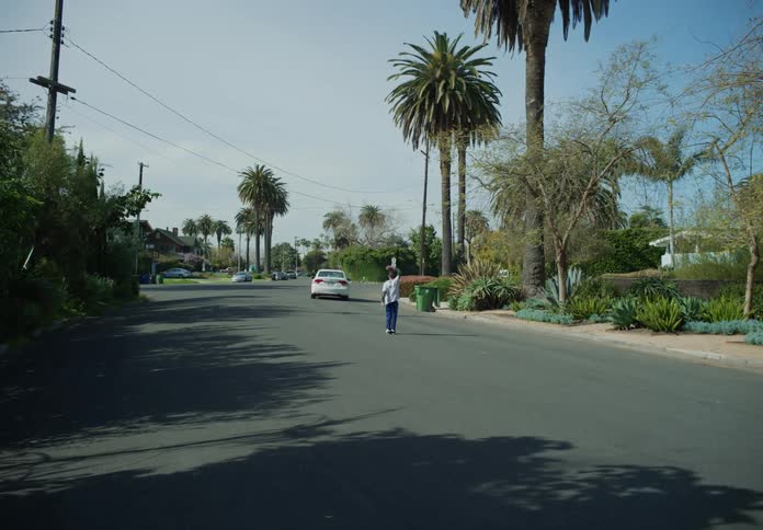 Young boy running after white car driving away stopping and waving