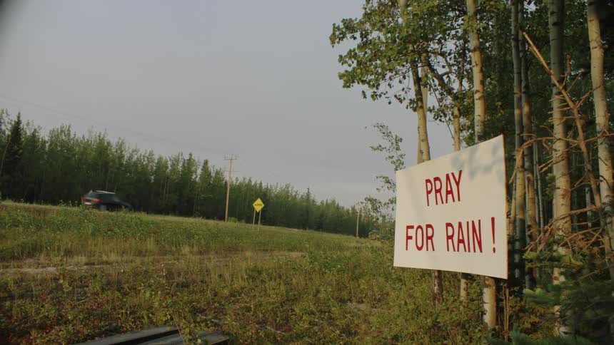 A sign on the side of the road says pray for rain