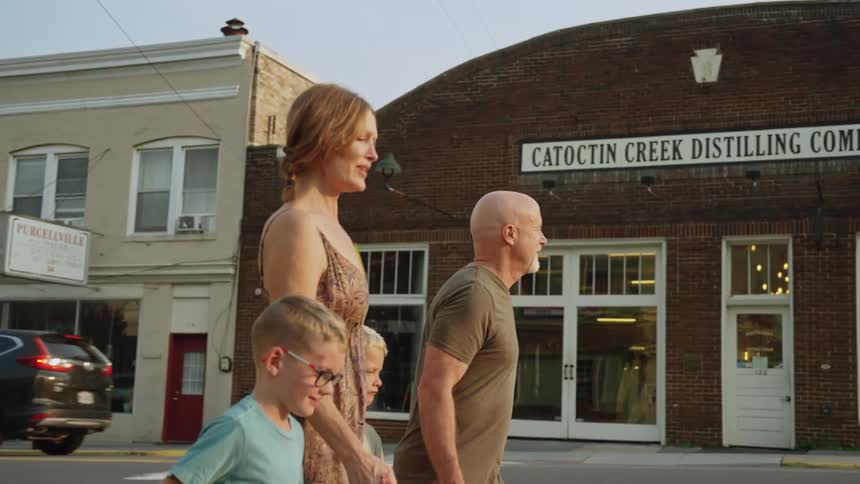 Parents with their kids walk along town while holding the childrens hands
