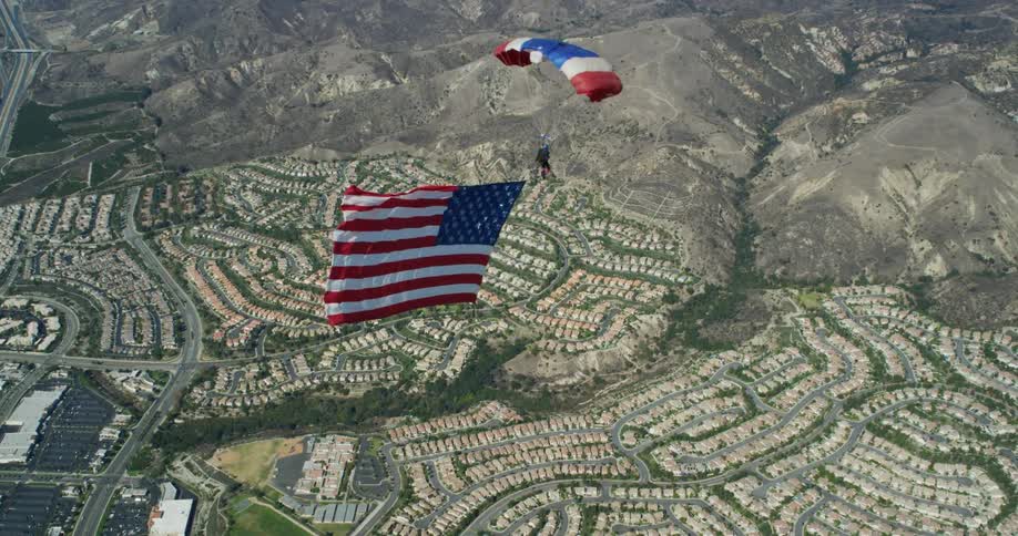 A person para sailing with a red white and blue sail while dragging a large american flag behind them