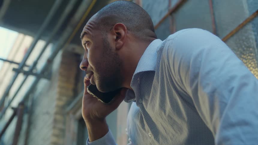 A man is sitting outdoors and talking on the phone