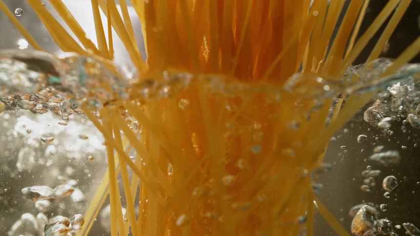 Uncooked spaghetti noodles falling into a pot of boiling water