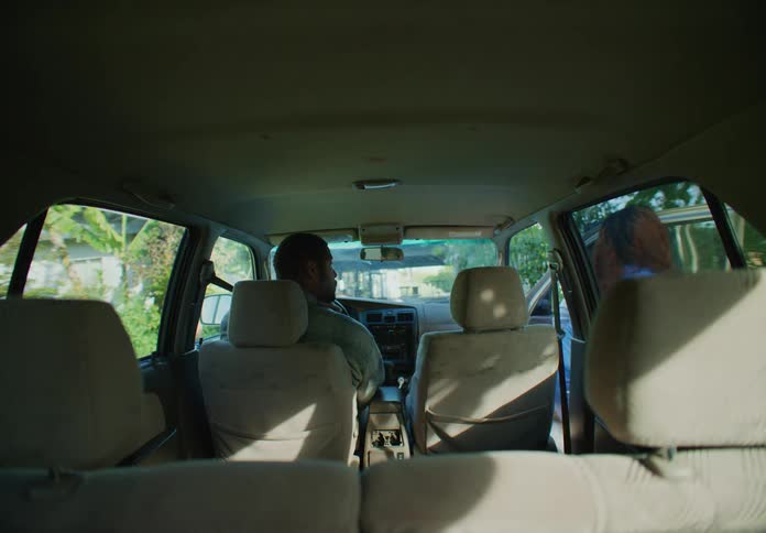 Man and woman are sitting in a car together in a neighborhood