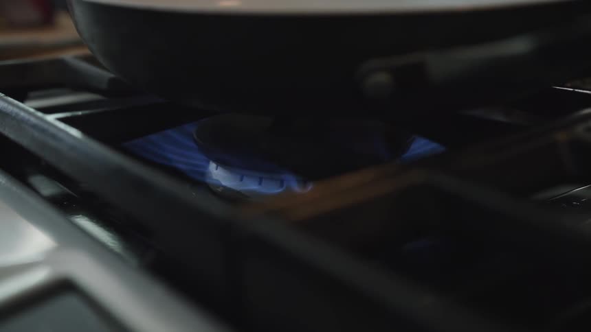 Flame turning on from burner on gas stove under a metal pot
