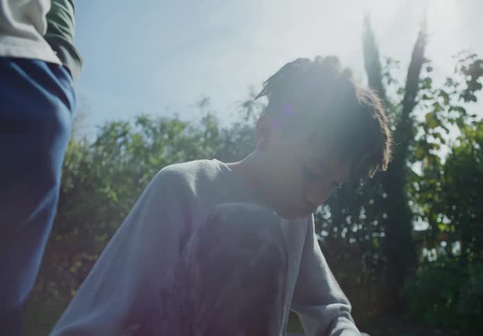 A boy stops walking on a trail to tie his shoe