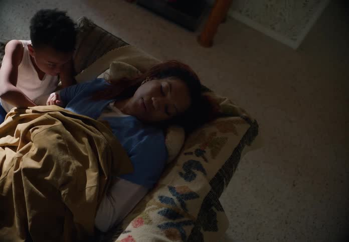 Young boy carefully wakes up his mother sleeping in the couch at home