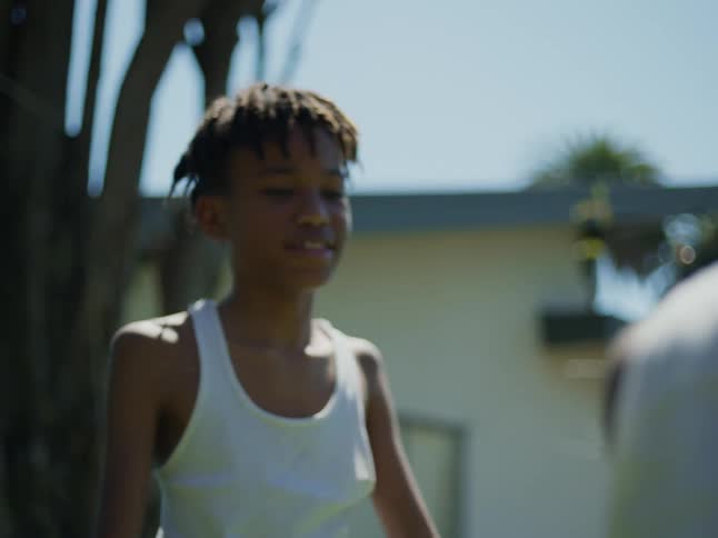 Boy touches the shoulder of his brother playing in the backyard at home at daytime
