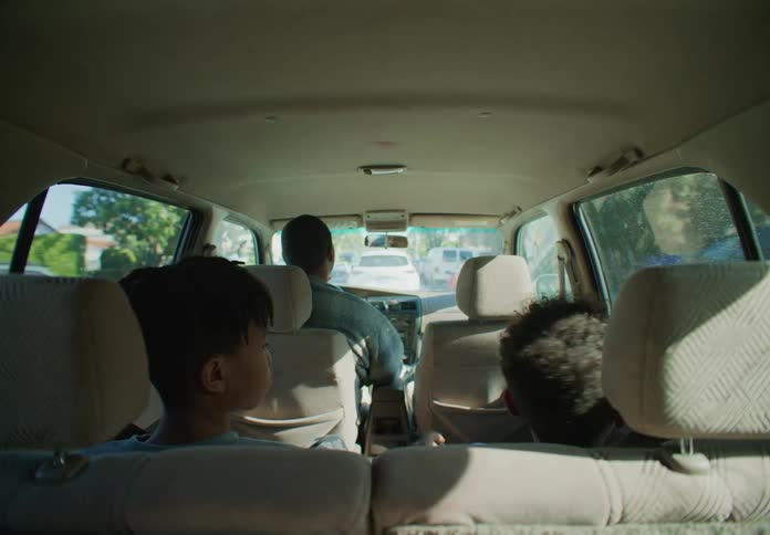 Two children in the back seat of a car as their father drivers the car