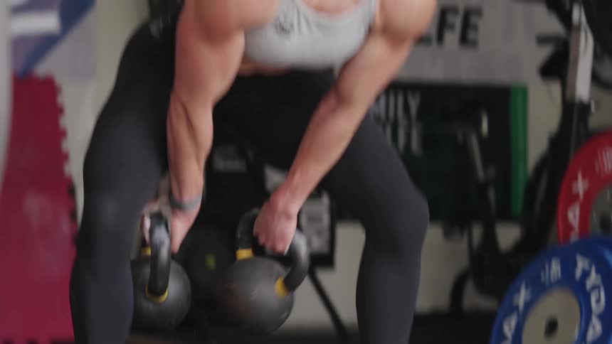 Close up of the face and arms of a strong muscular woman lifting weights over her head