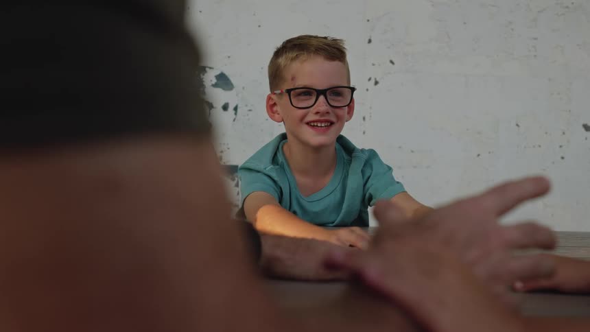 A boy smiles while landing his hand on the table