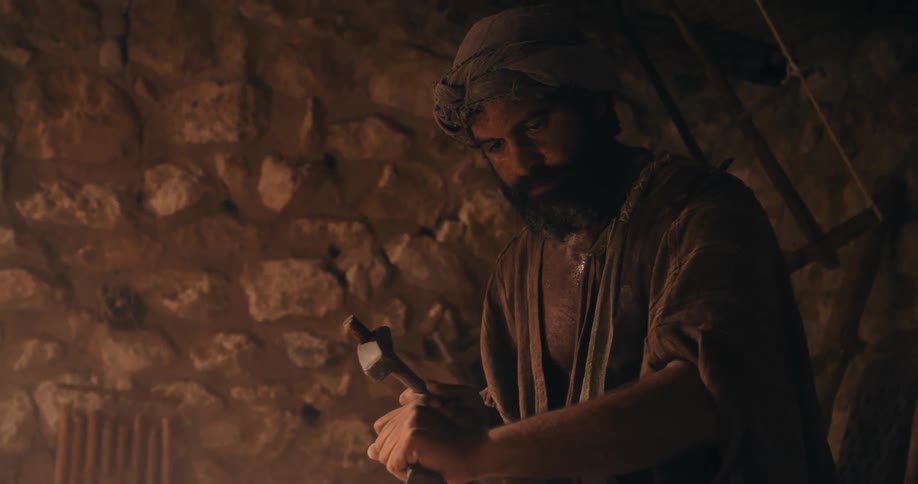 Traditional middle east stonemason carving a rock with hammer and chisel