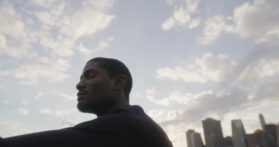 A man is sitting outdoors near a downtown city