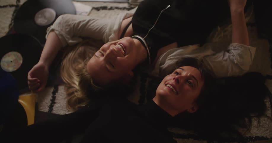 Two women laugh and talk on the floor