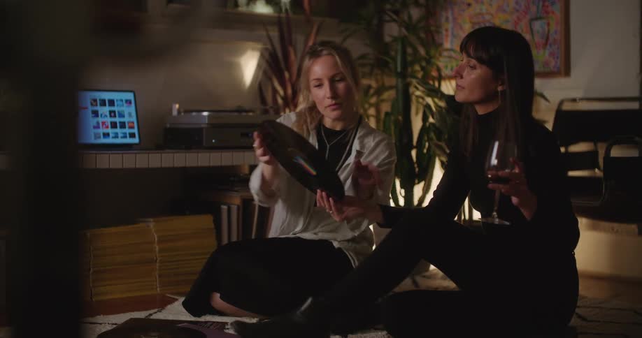 Two people drinking wine and looking at records