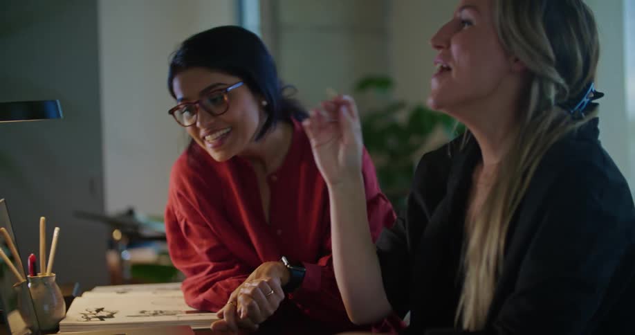 Two women talk while looking at a laptop