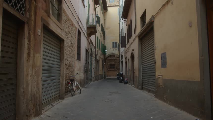 A bicycle is parked on the side of an alley during the day