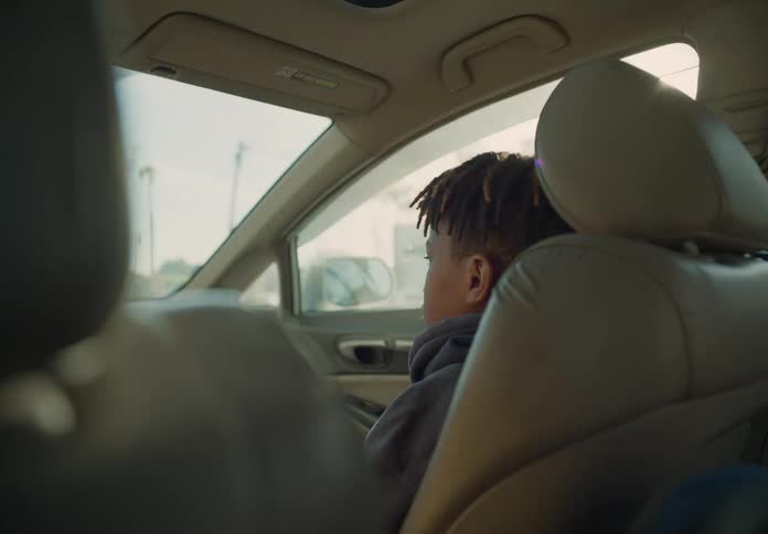 A young boy is sitting in the passenger seat of an automobile as it travels through the suburbs