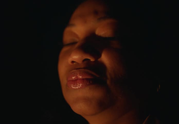 Woman standing inside a dark room during a blackout comes into focus looking at the camera