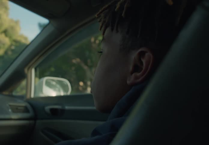 A young boy is sitting in the passenger seat of an automobile as it travels through a neighborhood