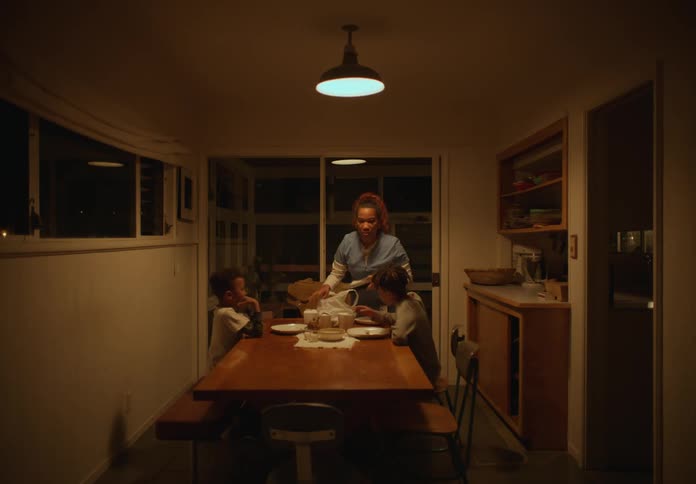 A woman and two boys walk into a dining room and place a bag on the table