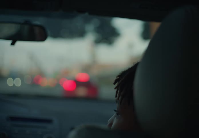 Teen boy riding in the passenger side of car with mom early evening