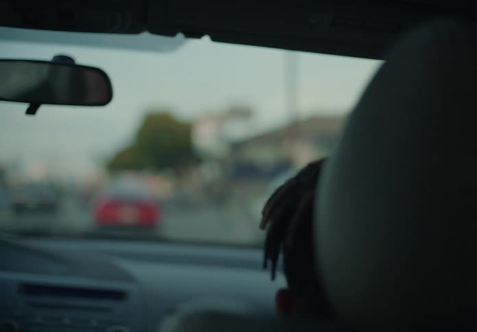 Boy with dreadlocks sits in car driving on highrway