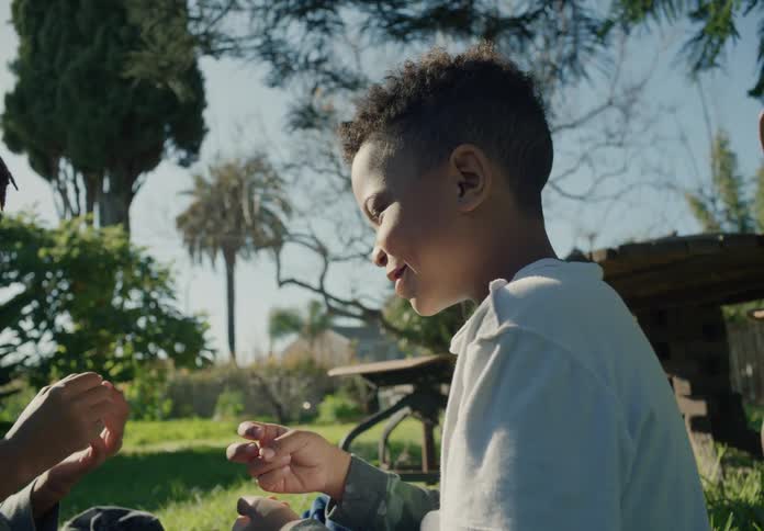 Two young boys sitting on the lawn playing rock paper scissors