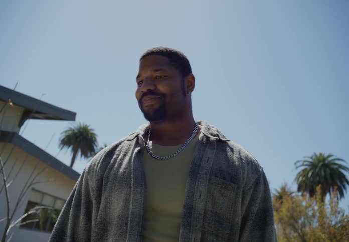Man standing in the backyard at home talking to his son under a blue sky