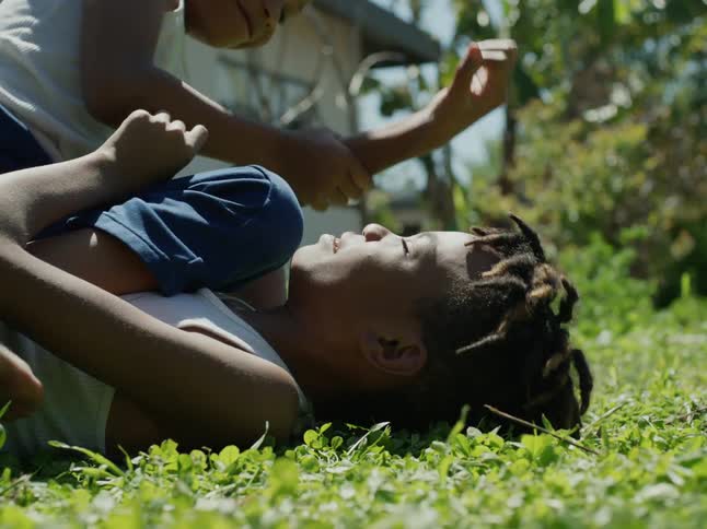 Two boys play fight in their yard