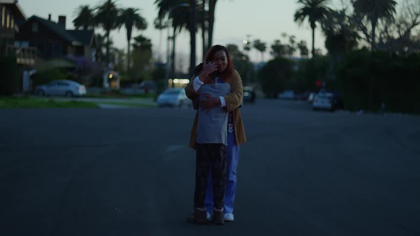 A woman hugs a boy and then watches as he runs out of frame