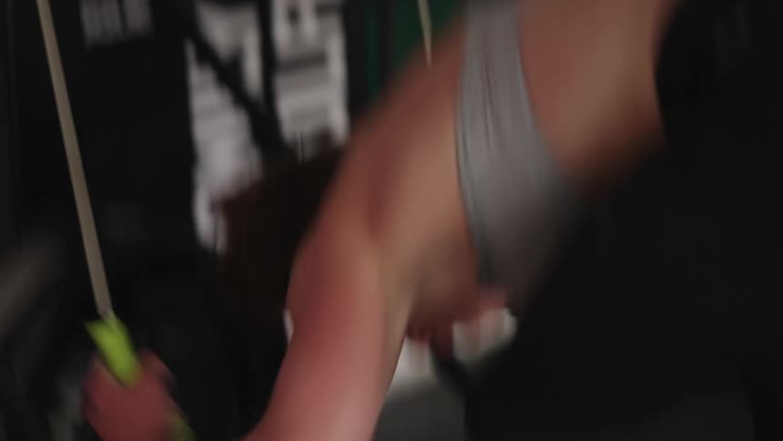 A woman working out aggressively and pulling exercise bands down