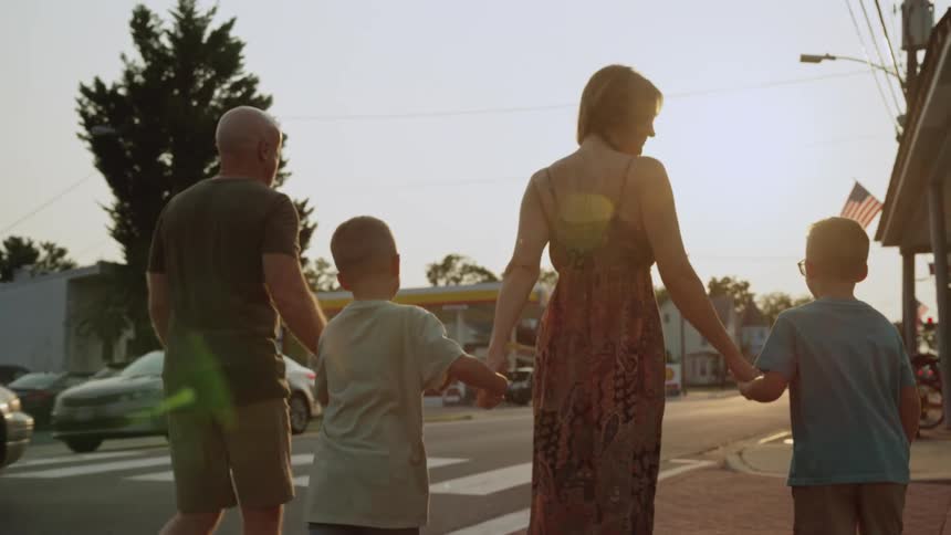 Family walk down the street of a town holding hands at evening