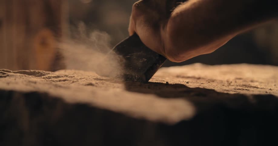 Close up of a man using a hammer and chisel to shape stone