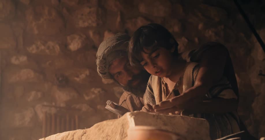 Traditional middle east stonemason teaching his son to carve a rock with hammer and chisel