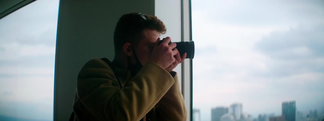 A man takes pictures of the city skyline from inside a building