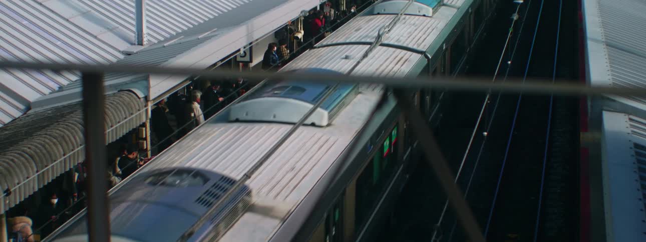 People waiting at a train station while a train is in motion