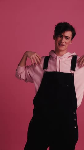 A white male teenager poses with his arms outstretched while laughing