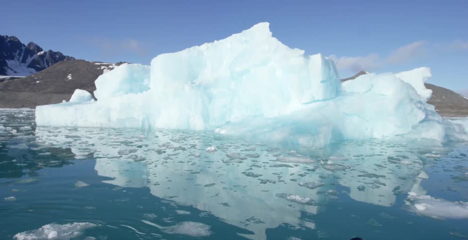 A large iceberg floats in the water on a sunny day
