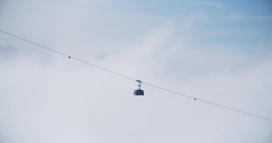 Ski lift returning downhill against a white out background and mountains