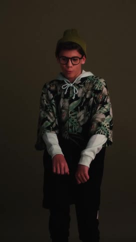 A teenage boy dances as he poses in a studio