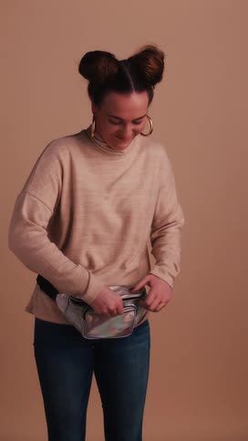A teenager unzips a fanny pack as she smiles for a camera