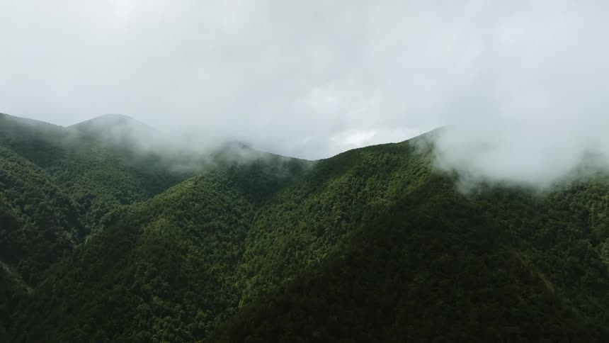 Clouds float over a mountain range covered in dense vegetation
