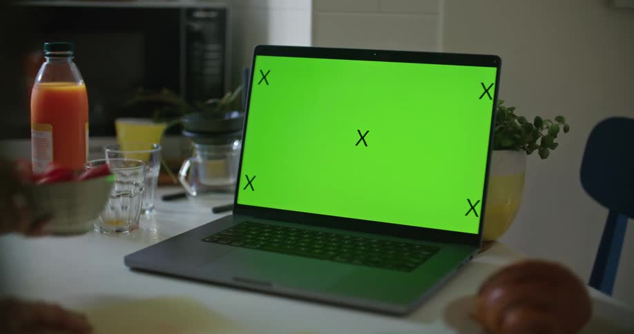 Womans hand takes a bowl of strawberries next to laptop on the table
