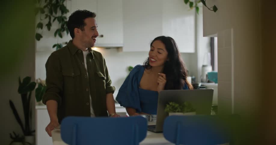 A man and woman smile and talk while they look at a laptop screen