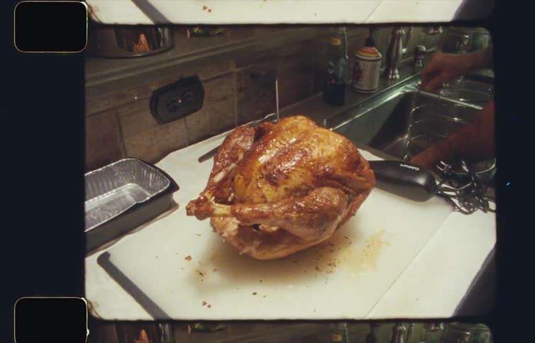 A fully cooked turkey is atop a cutting board next to a sink