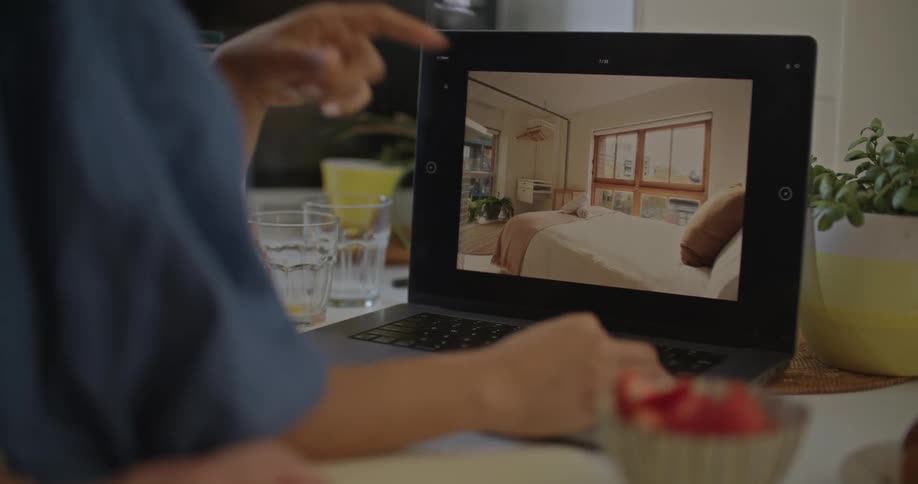 Woman looking at home decor on laptop with fiance while standing at breakfast bar in kitchen