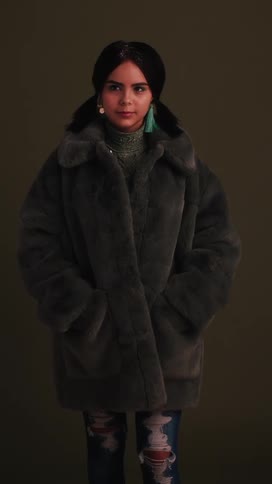 A hispanic girl smiles while wearing a heavy coat