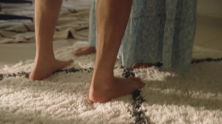 Man and woman slow dancing together at home in the living room we can see only feet on the ground