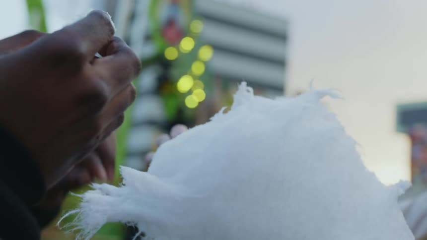 Eating white cotton candy outdoors at the fair