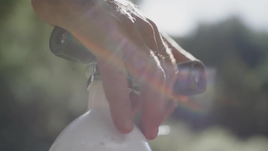 A man uses his fingers to loosen a knob on a pressurized container